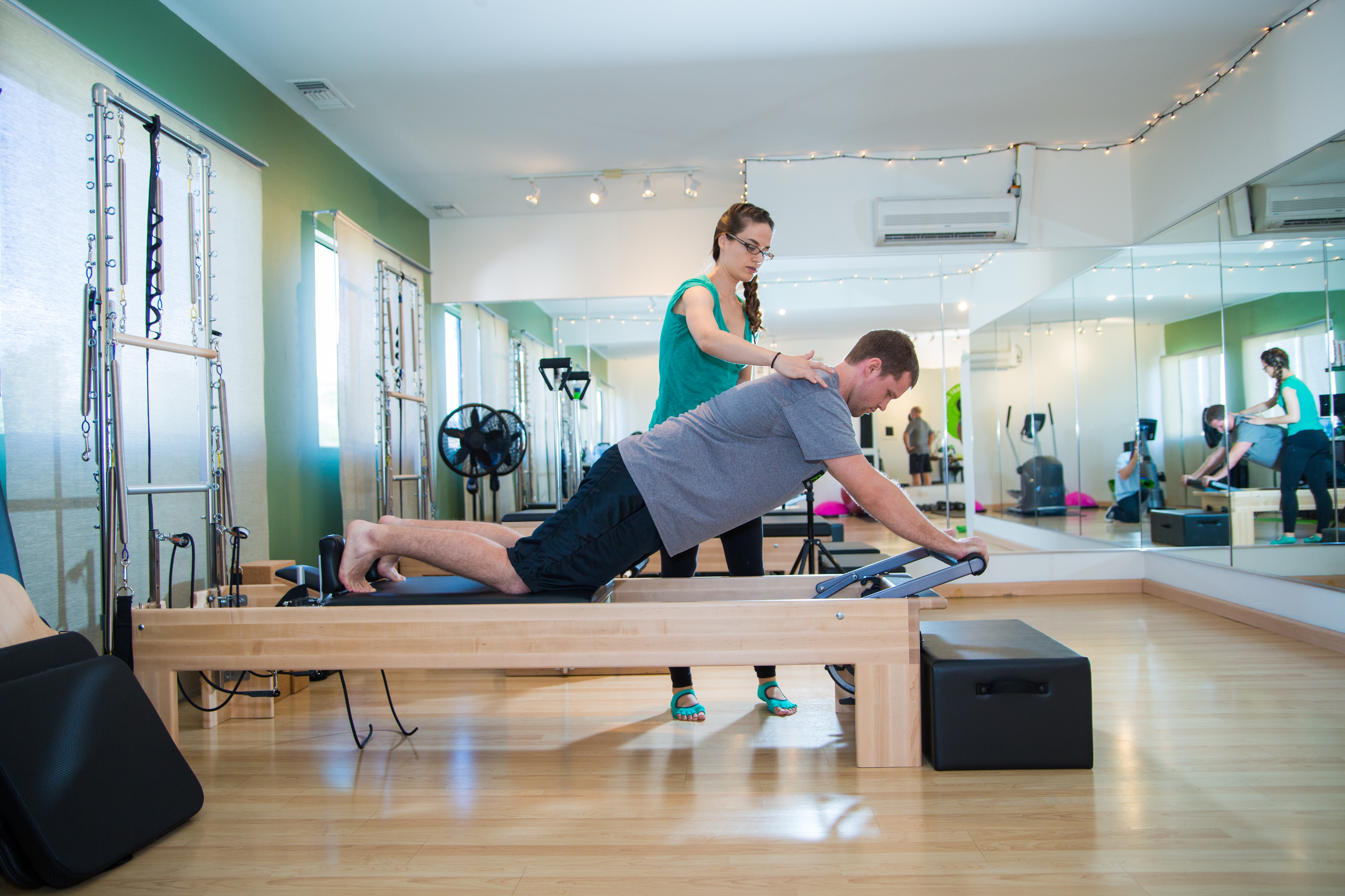 Fit Monkeys instructor providing one-on-one Pilates instruction to a client on the reformer in the Carlsbad studio.